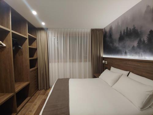 ein Schlafzimmer mit einem weißen Bett und einem Gemälde an der Wand in der Unterkunft Chalet Bello in Livigno