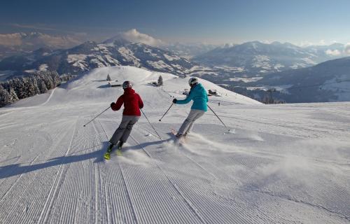 two people are skiing down a snow covered slope at Appartement Margreiter in Niederau