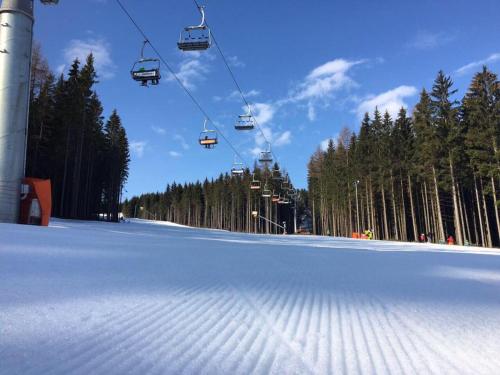 a ski lift on a snow covered slope with trees at Chata pod lesem in Rýmařov