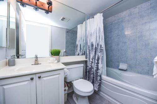 a bathroom with a white toilet and a sink and a tub at PlanURstay - Luxury 1BR Condo with City View in Mississauga