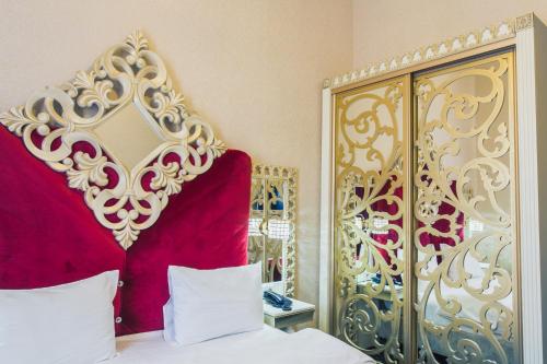 a bedroom with a bed and a red and gold headboard at Отель НЕАПОЛЬ in Moscow