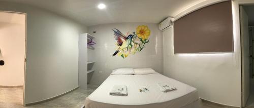 1 dormitorio con 1 cama con una pintura en la pared en Casa Ilaria en Cartagena de Indias