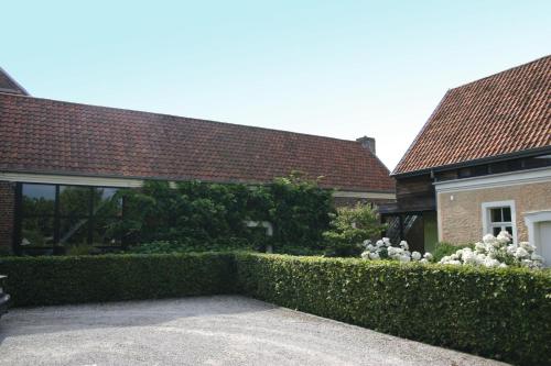 a hedge in front of a house with white flowers at Loft ça suffit, Eddy! in Zingem