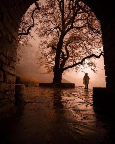 a person walking down a sidewalk with a tree at Papaevangelou Hotel in Papigko