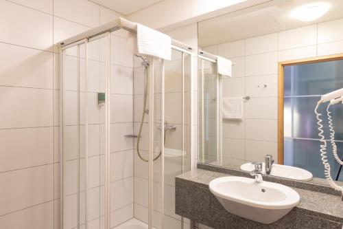a bathroom with a shower, sink, and mirror at Hotel Bokan Exclusiv in Graz
