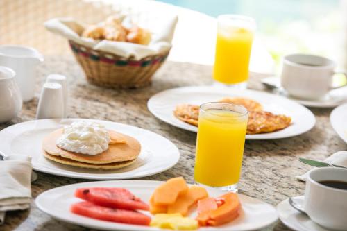 a table with plates of food and two glasses of orange juice at Hotel Boutique Don Pepe in Santa Marta