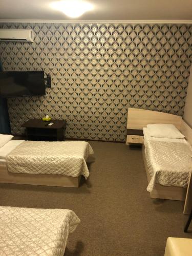 a room with two beds and a wall with a wallpaper at Mereke Hotel in Ustʼ-Kamenogorsk