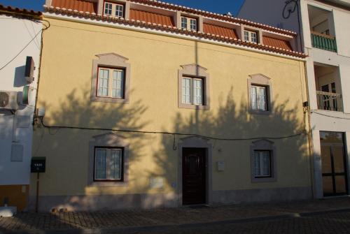 a yellow building with a tree shadow on the side of it at Casa do Coreto in Crato