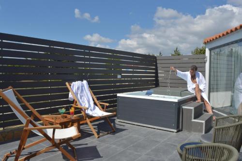 a man sitting on a patio with a hot tub at Anagenessis Resort in Kalamaki