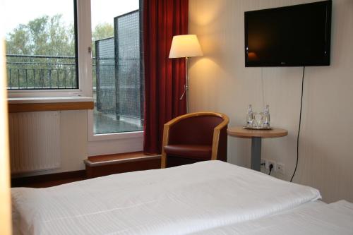 a hotel room with a bed and a chair and a television at Bildungszentrum Erkner in Erkner