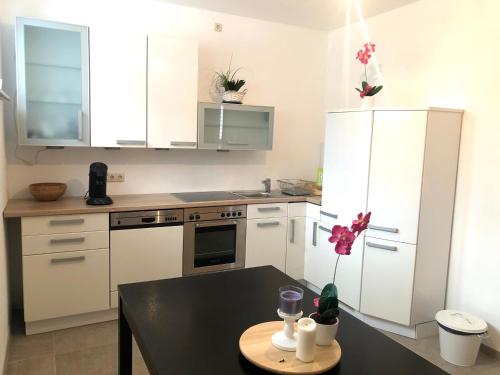 a kitchen with white cabinets and a black table at Herrmann-Apartments in Hannover
