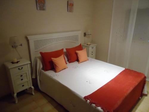 een slaapkamer met een wit bed met oranje kussens bij Nova Peñiscola Holidays LEK in Peñíscola