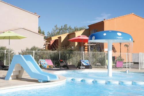 a swimming pool with a slide and an umbrella at Lagrange Vacances L’Oustau de Sorgue in LʼIsle-sur-la-Sorgue