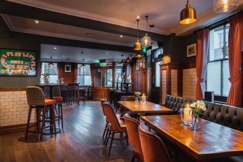 un ristorante con tavoli e sedie in legno e un bar di Albert Arms a Esher
