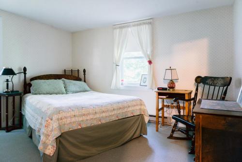 een slaapkamer met een bed, een bureau en een raam bij Carriage Barn Inn in Keene