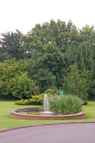 a fountain in the middle of a park with trees at Royal Court Hotel & Spa Coventry in Coventry