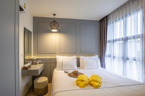 a bedroom with a bed with yellow towels on it at Surin Beach Residence in Surin Beach