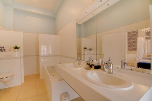 a white bathroom with two sinks and a toilet at Maison d'hôtes La Villa des Ducs Bar-le-Duc in Bar-le-Duc