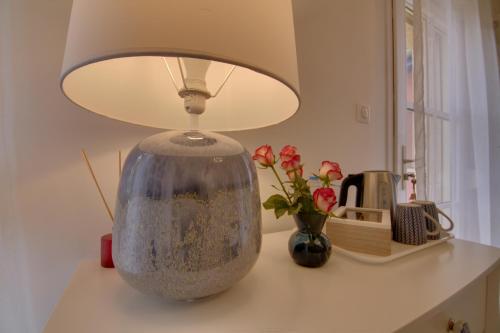 a lamp on a table with a vase and flowers at Maison d'hôtes La Villa des Ducs Bar-le-Duc in Bar-le-Duc