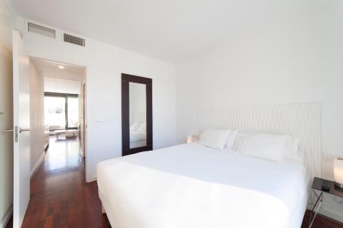 sypialnia z dużym białym łóżkiem i lustrem w obiekcie Ático Valencia Centro w Walencji