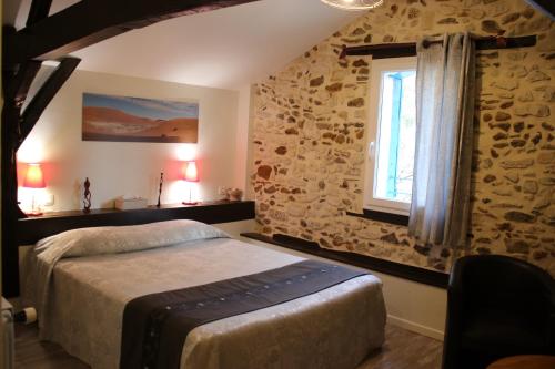 a bedroom with a bed and a stone wall at Chambre d'Hôtes au Sargaillon in Pouillon
