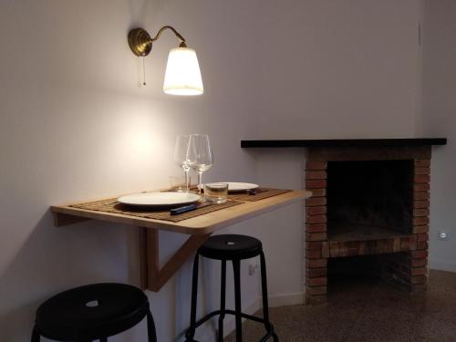 una mesa con 2 copas de vino y una chimenea en Apartamento 2 Cal Genís - WIFI, en Montmajor
