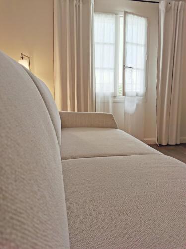 a white couch in a room with a window at Le Clos Saint-Martin Hôtel & Spa in Saint-Martin-de-Ré