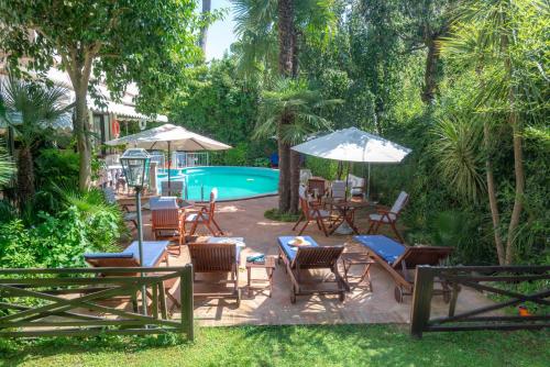a patio with chairs and umbrellas next to a pool at Hotel Kyrton in Forte dei Marmi