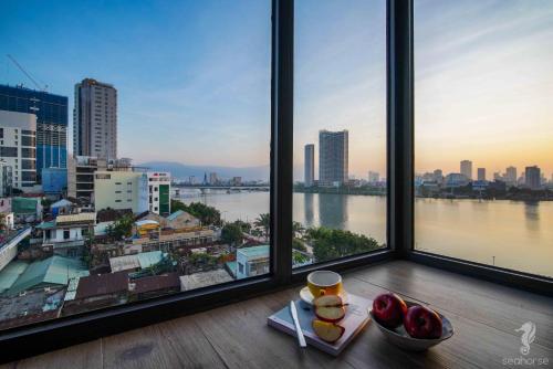 a view of a city from a window with a bowl of fruit at Seahorse Han Market Da Nang Apartment by Haviland in Danang