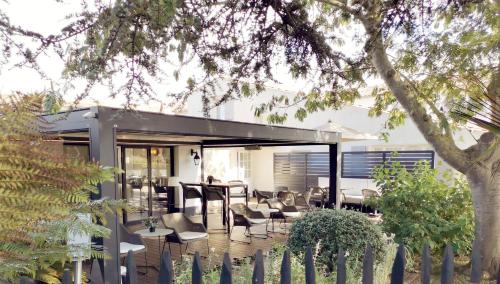 a house with a deck with chairs and a table at Le Clos Saint-Martin Hôtel & Spa in Saint-Martin-de-Ré