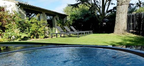 a swimming pool in a yard with chairs and a tree at Le Clos Saint-Martin Hôtel & Spa in Saint-Martin-de-Ré