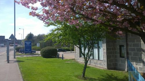 uma árvore com flores cor-de-rosa ao lado de um edifício em Britannia Hotel Aberdeen em Aberdeen