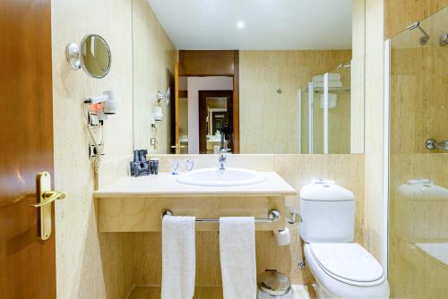 a bathroom with a sink and a toilet and a mirror at Amura Alcobendas in Alcobendas