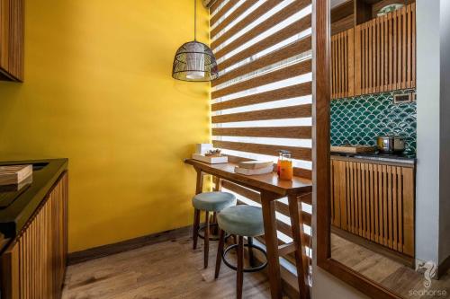 a kitchen with a bar with stools and a yellow wall at Seahorse Han Market Da Nang Apartment by Haviland in Danang