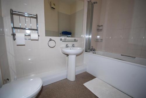 a bathroom with a sink and a toilet and a bath tub at Saltburn Holidays 1 Park View Loftus in Loftus