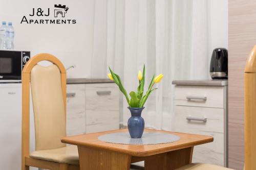 una mesa con un jarrón azul con flores amarillas. en J&J Apartments, Łazienna 30 Apartament 8/2, en Toruń