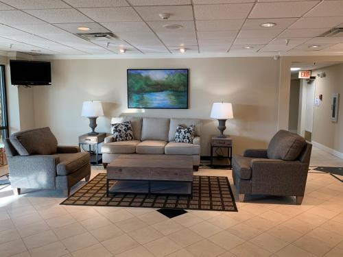 a lobby with a couch and two chairs and a tv at Baymont by Wyndham Latham Albany Airport in Latham