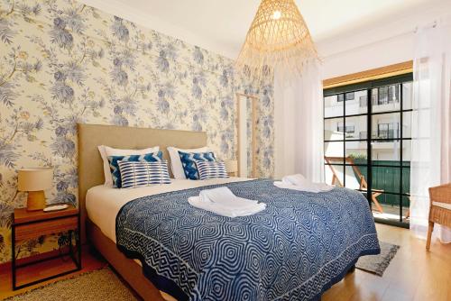 Un dormitorio con una cama azul y blanca y una lámpara de araña. en Gorgeous Beach Apartment - Checkinhome en Carcavelos