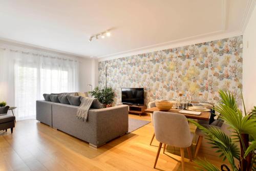 a living room with a couch and a table and a tv at Gorgeous Beach Apartment - Checkinhome in Carcavelos