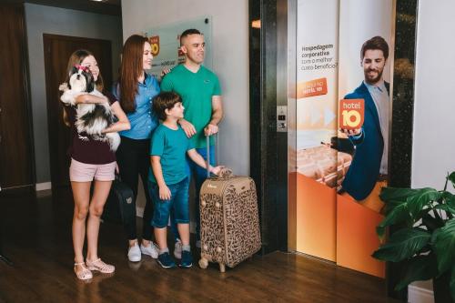 a family posing for a picture with a suitcase at Hotel 10 Itajai/Navegantes in Itajaí