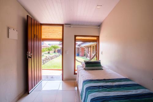 a bedroom with a bed and a door to a yard at Pousada Muito Bonito in Bonito