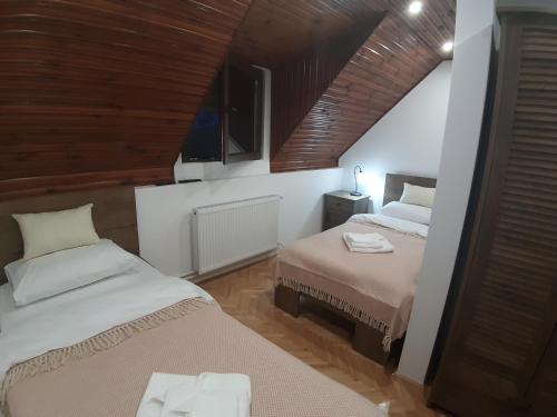 a bedroom with two beds and a wooden ceiling at Maison ALANA in Divčibare