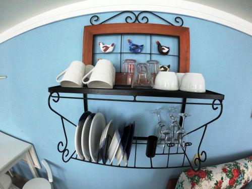 un estante con platos y utensilios en una pared azul en Recanto do Lago Buzios, en Búzios