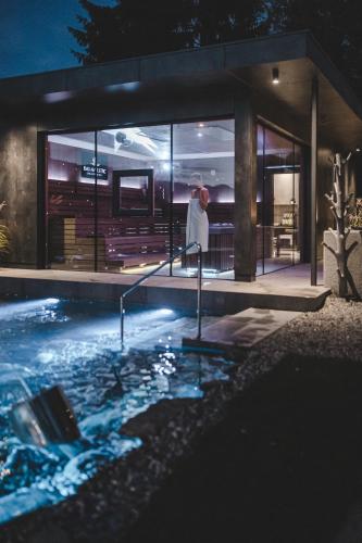 a woman in a white dress standing in a swimming pool at night at Majestic - Unique Spa Resort in Brunico