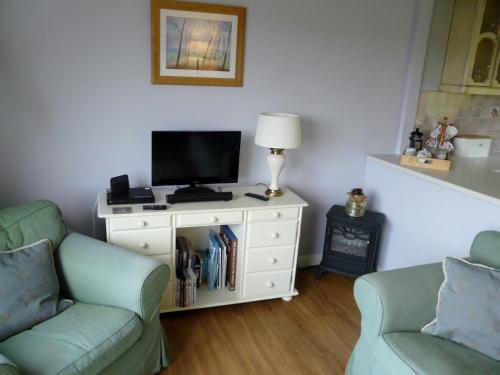 ein Wohnzimmer mit 2 Stühlen und einem TV auf einem Schrank in der Unterkunft Tweed Cottage in Jedburgh