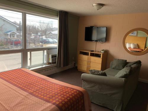 パースにあるPerth Plaza Inn & Suitesのベッドルーム(ベッド1台、テレビ、ソファ付)