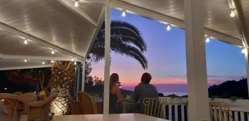 Un uomo e una donna seduti su un portico a guardare il tramonto di La Locanda della Castellana adults only a Peschici