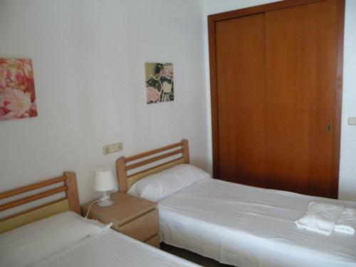 een slaapkamer met 2 bedden en een houten deur bij Torre Levante - Fincas Arena in Benidorm