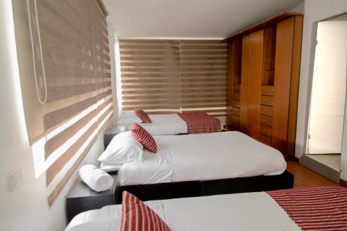 a room with three beds and a window at Deportel Bogotá in Bogotá