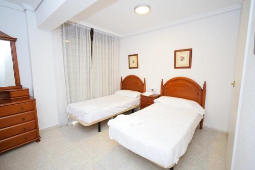a bedroom with two beds and a dresser at Las Tejas - Fincas Arena in Benidorm